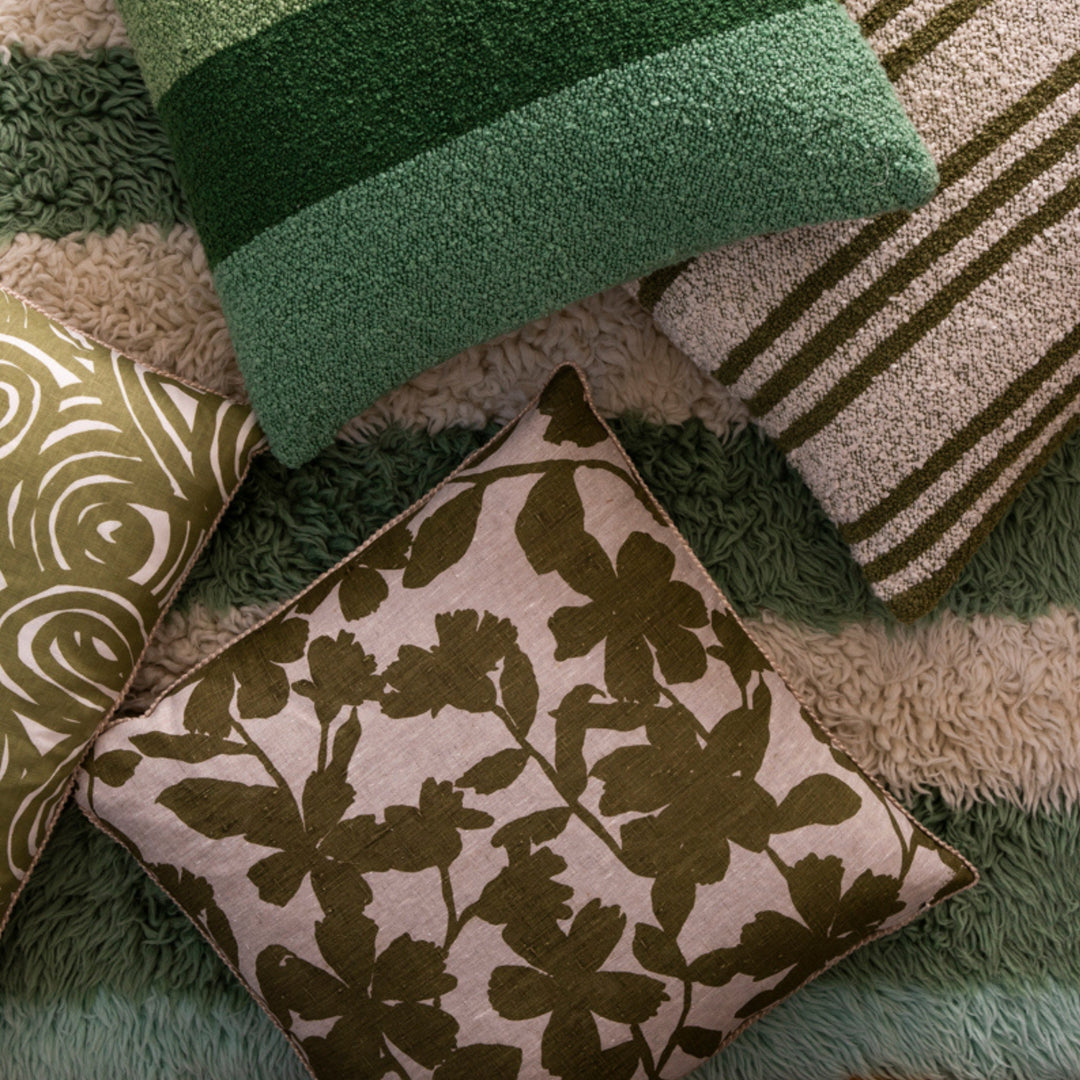 Geranium Khaki 60cm Linen Cushion Styled On Striped Rug With Complementary Cushions