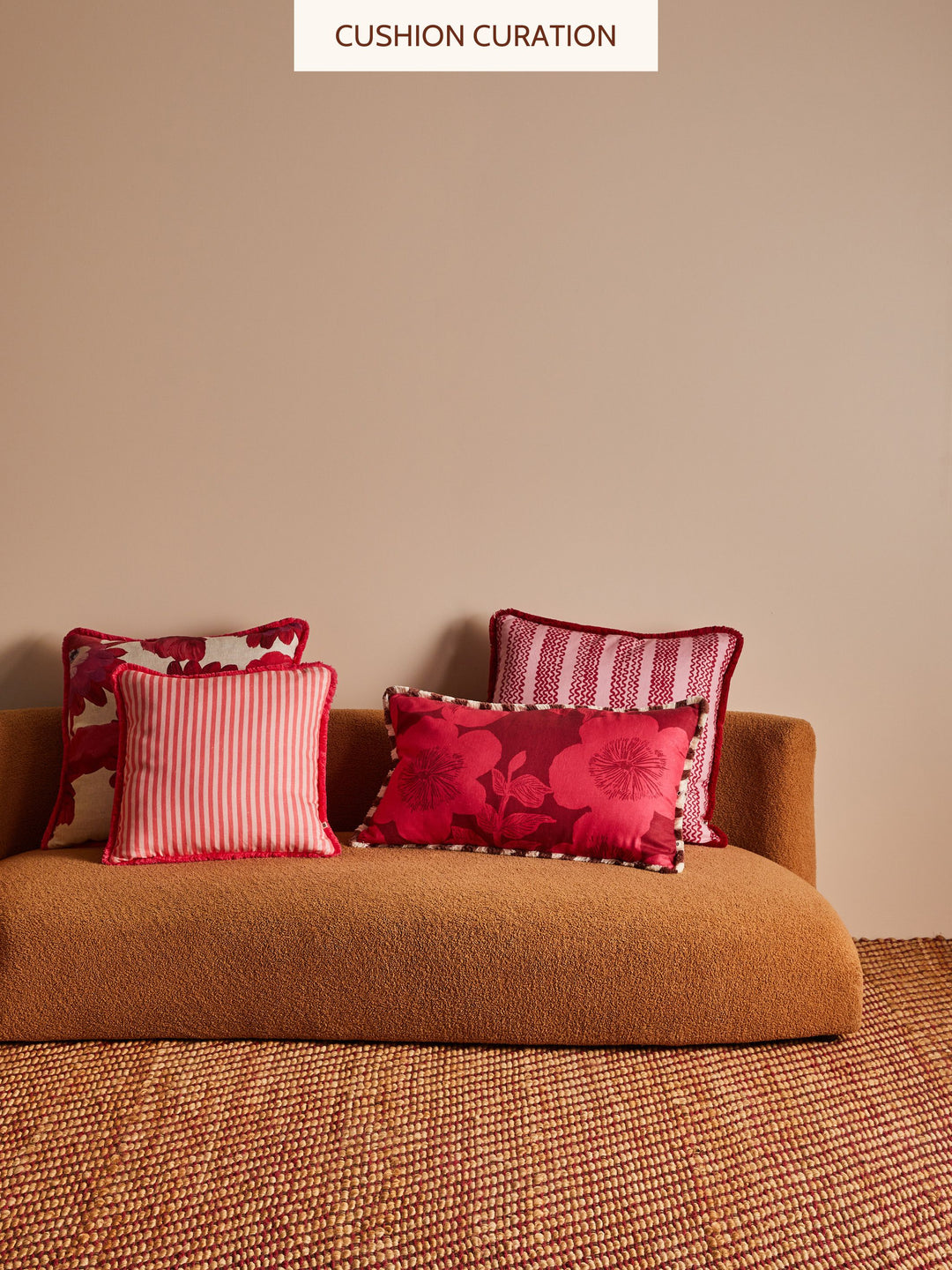 Brown sofa with red and patterned cushions against a beige wall