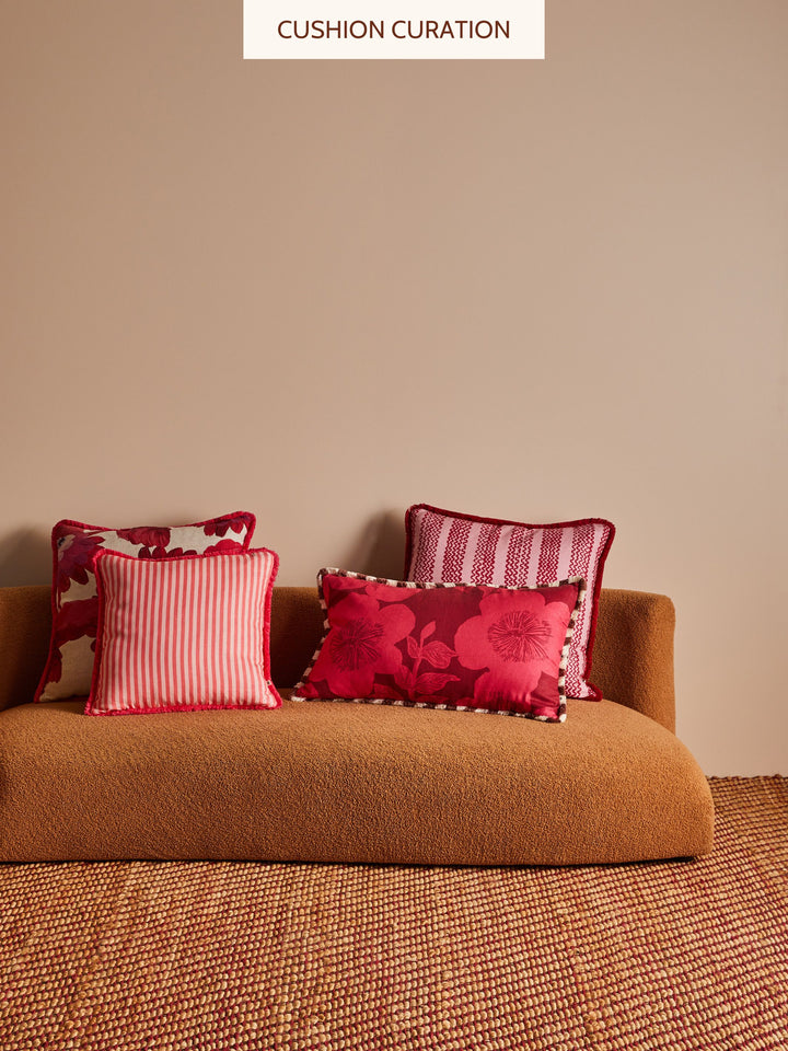 Brown sofa with red and patterned cushions against a beige wall