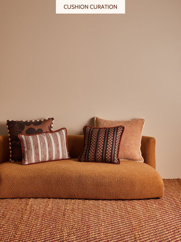 Brown sofa with brown patterned cushions against a beige wall