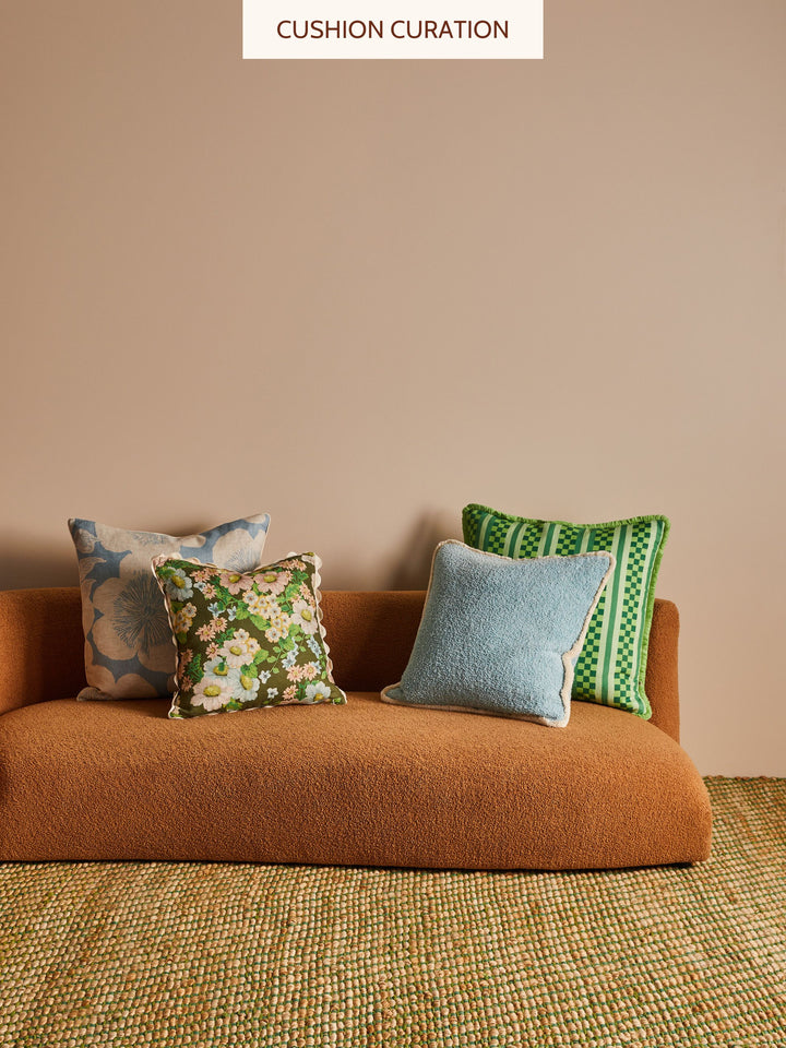 Brown sofa with blue and green cushions against a beige wall